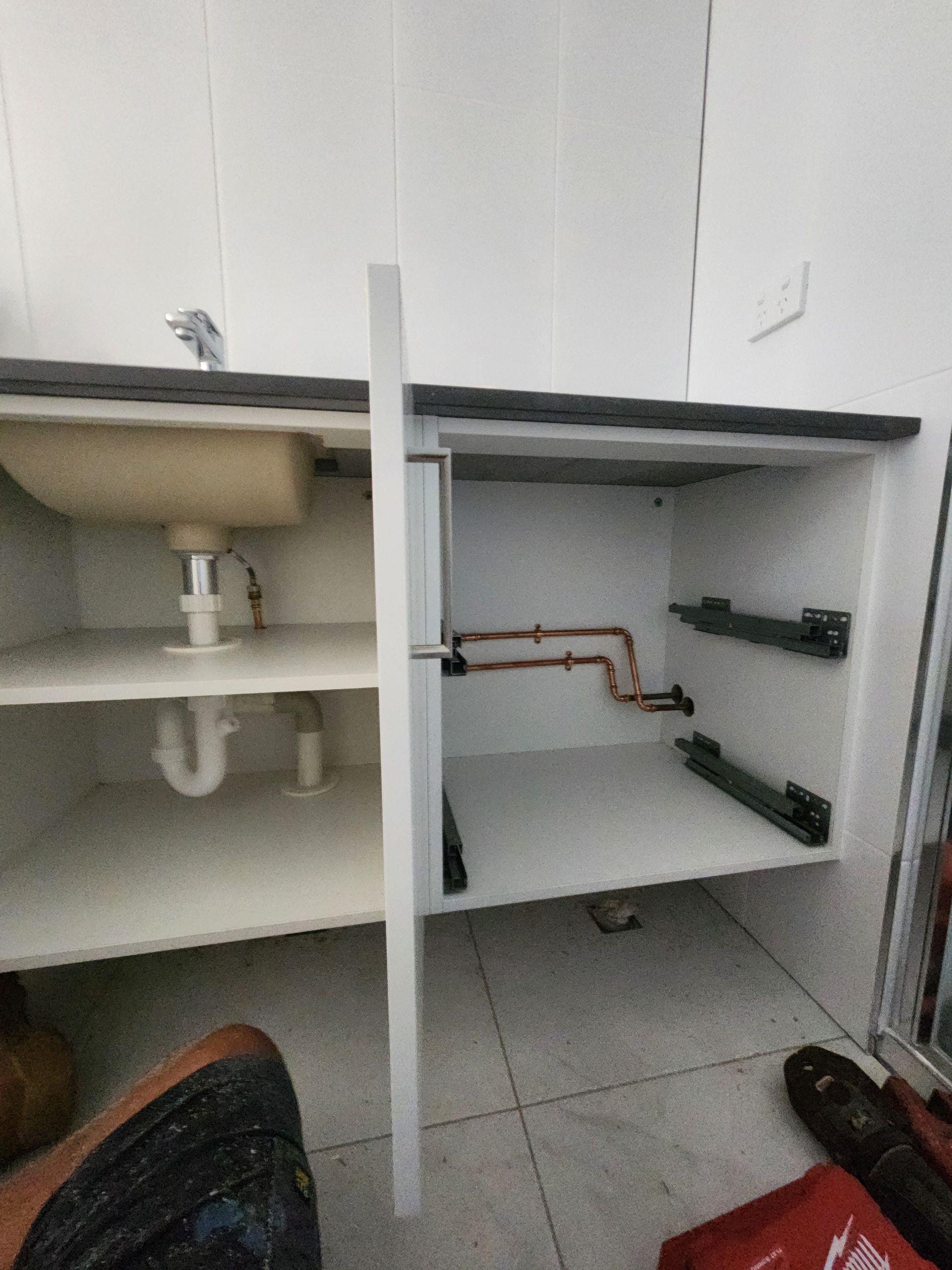A White Kitchen Cabinet With an Open Door — Kingdom Plumbing Services in Gordonvale, QLD