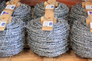 Several coiled rolls of silver barbed wire stacked on a wooden pallet.