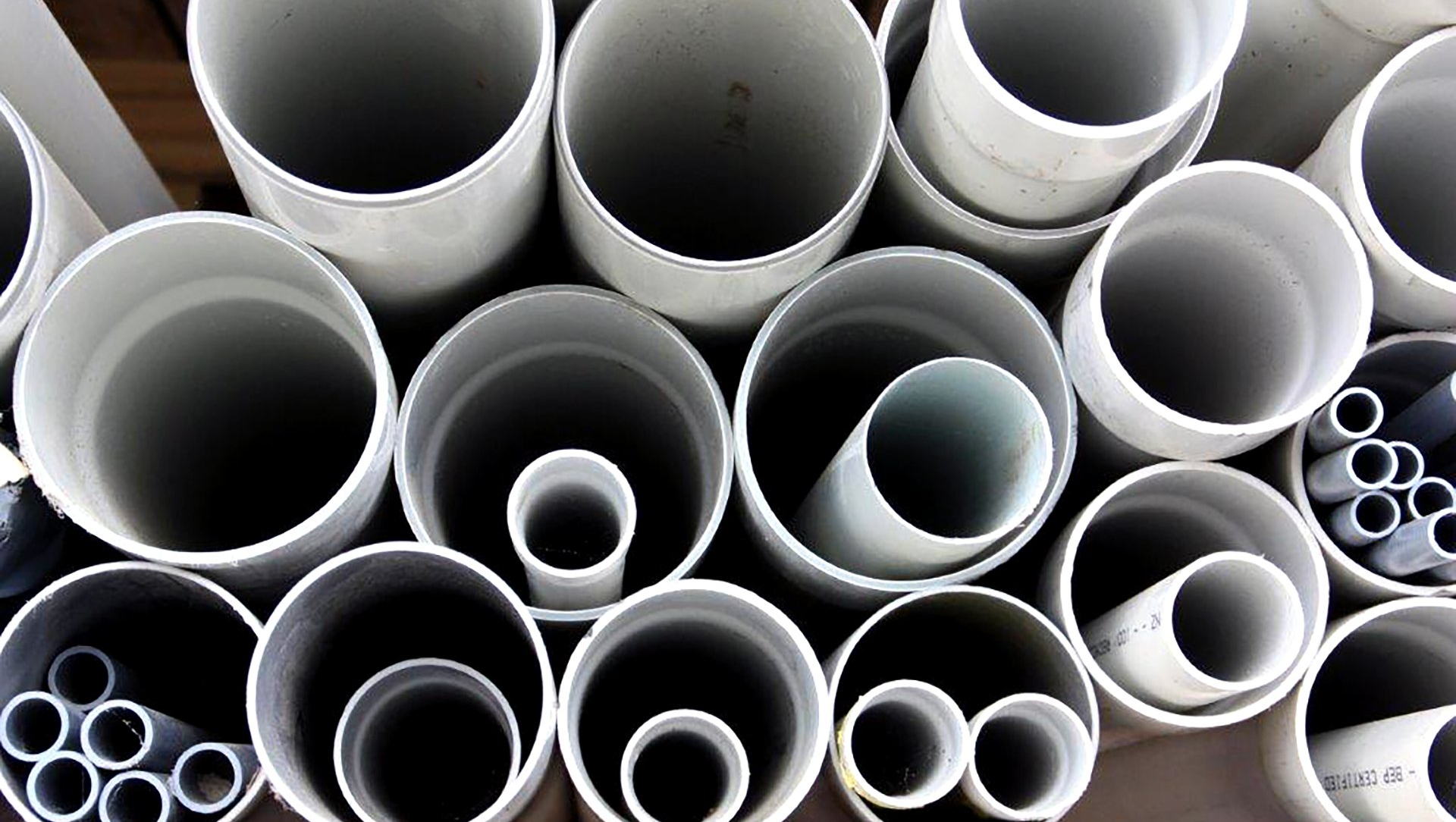 A top-down view of various sizes of white PVC pipes nested together in a bundle.