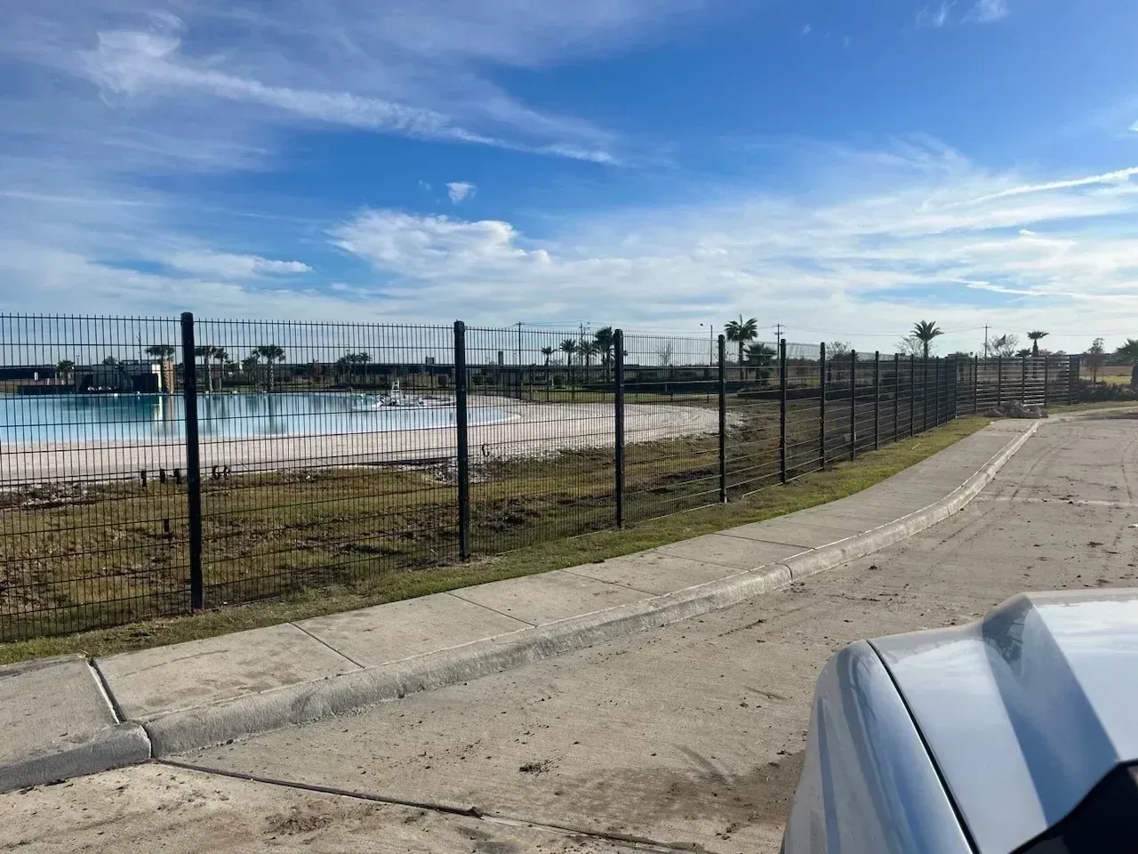 A fenced-off body of water with a concrete path and clear sky above.
