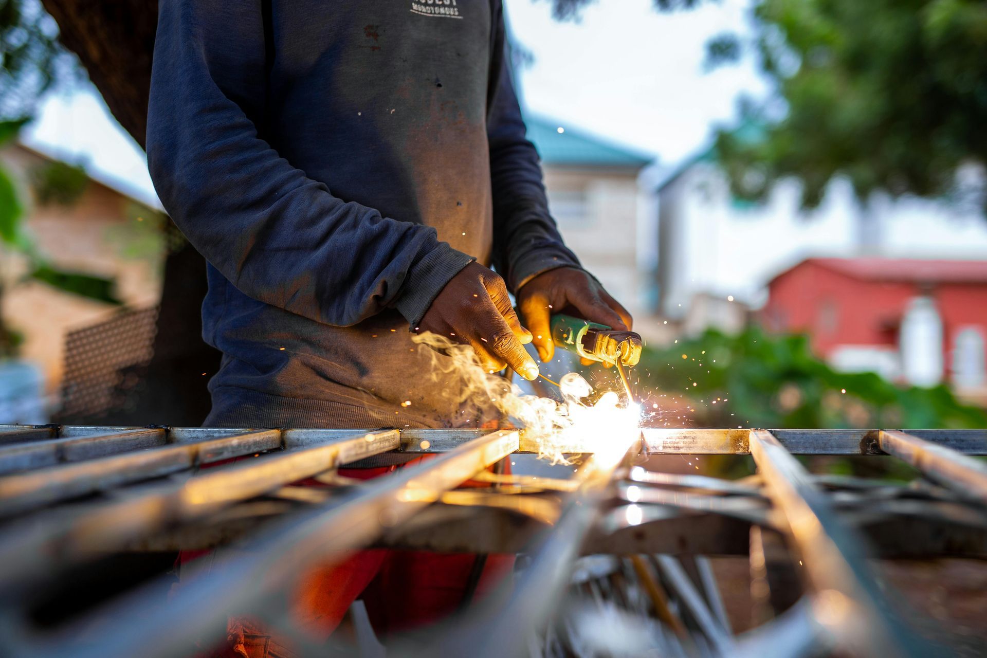 Person welding metal bars with bright sparks flying outdoors at a construction site
