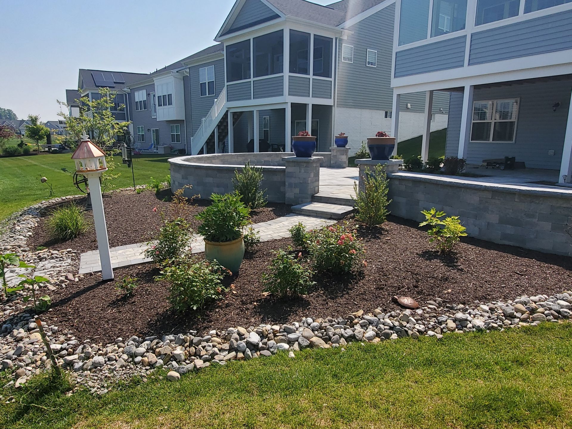 Backyard patio with landscaping, a fire pit, and a multi-story house.