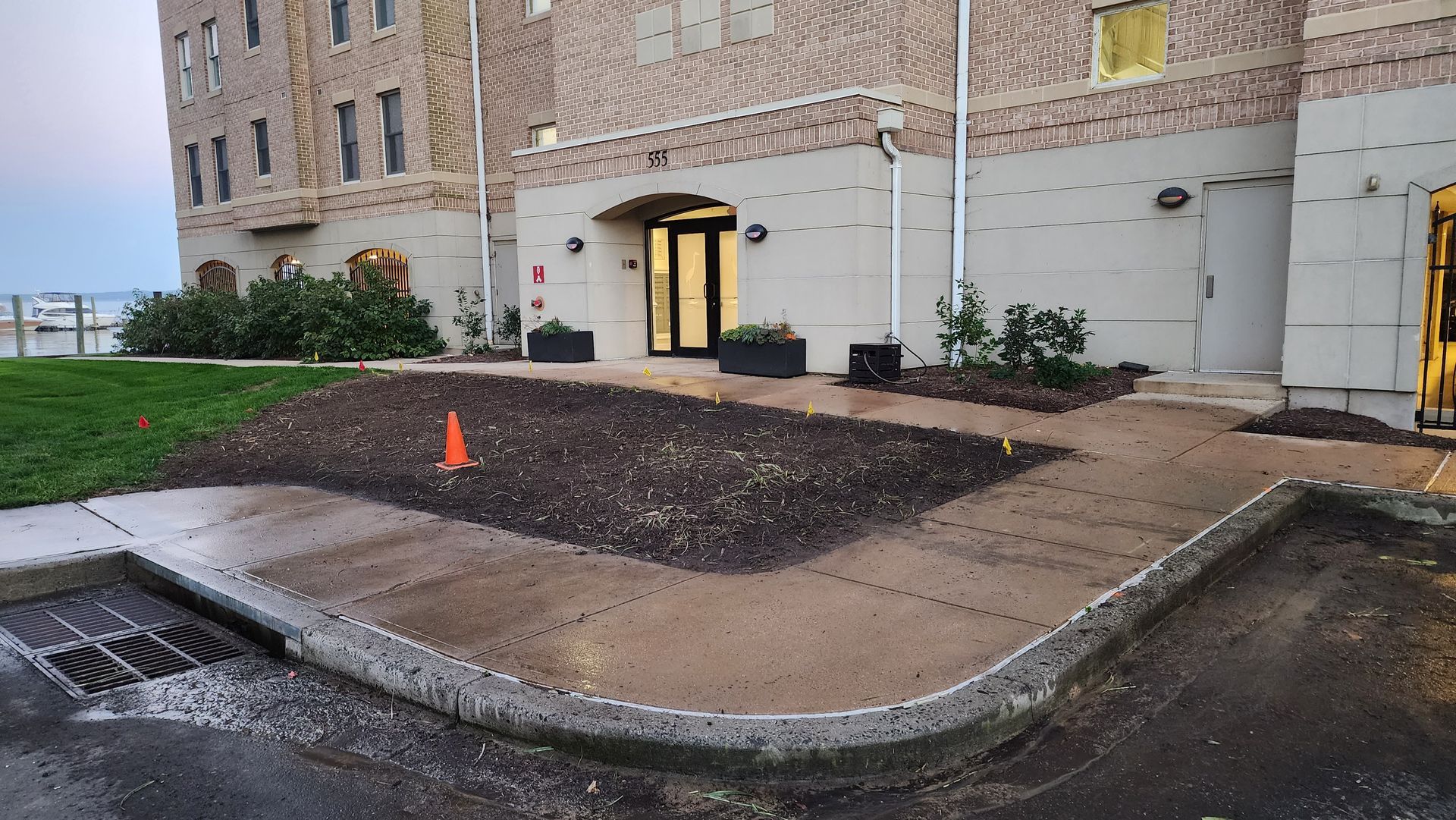 Building entrance with a ramp, newly planted bed, and an orange cone.