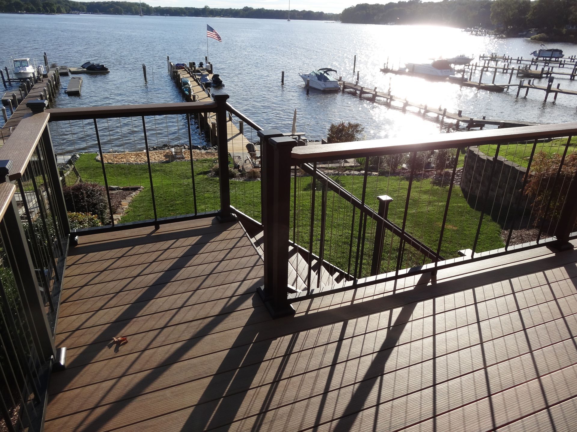 Wooden deck with metal railing overlooking a lake and docks with boats.