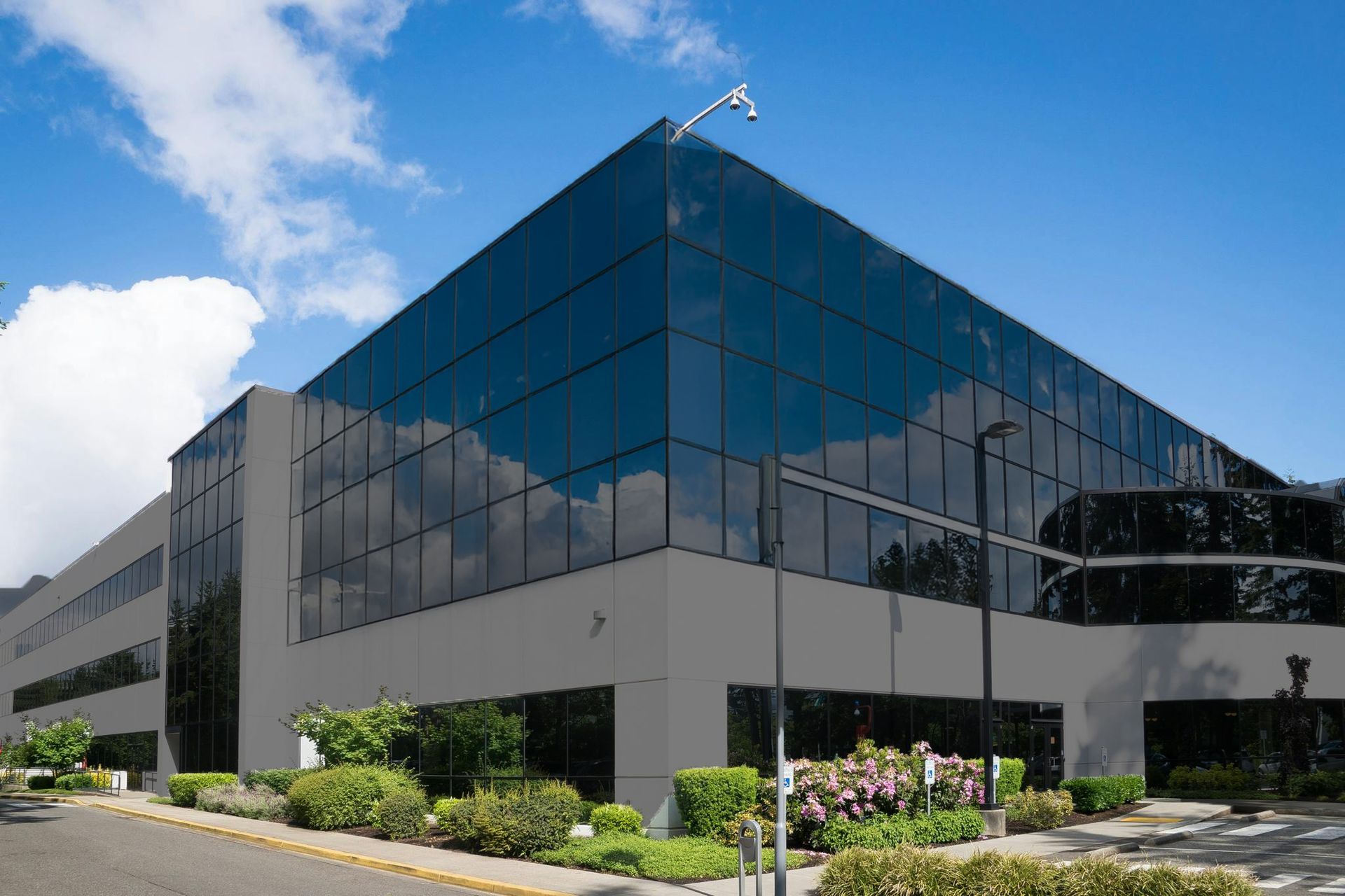 Modern commercial building with glass windows and a gray facade, under a blue sky.