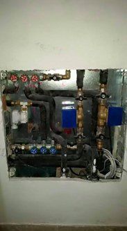 Unità idraulica e HVAC con tubi, valvole e isolamento contro una parete.