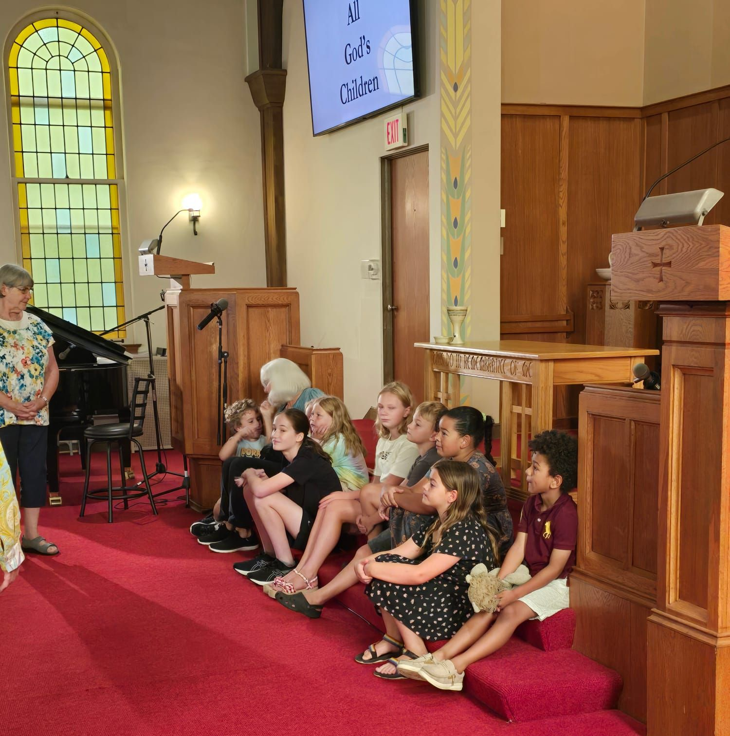 A group of children are standing next to each other holding green leaves.