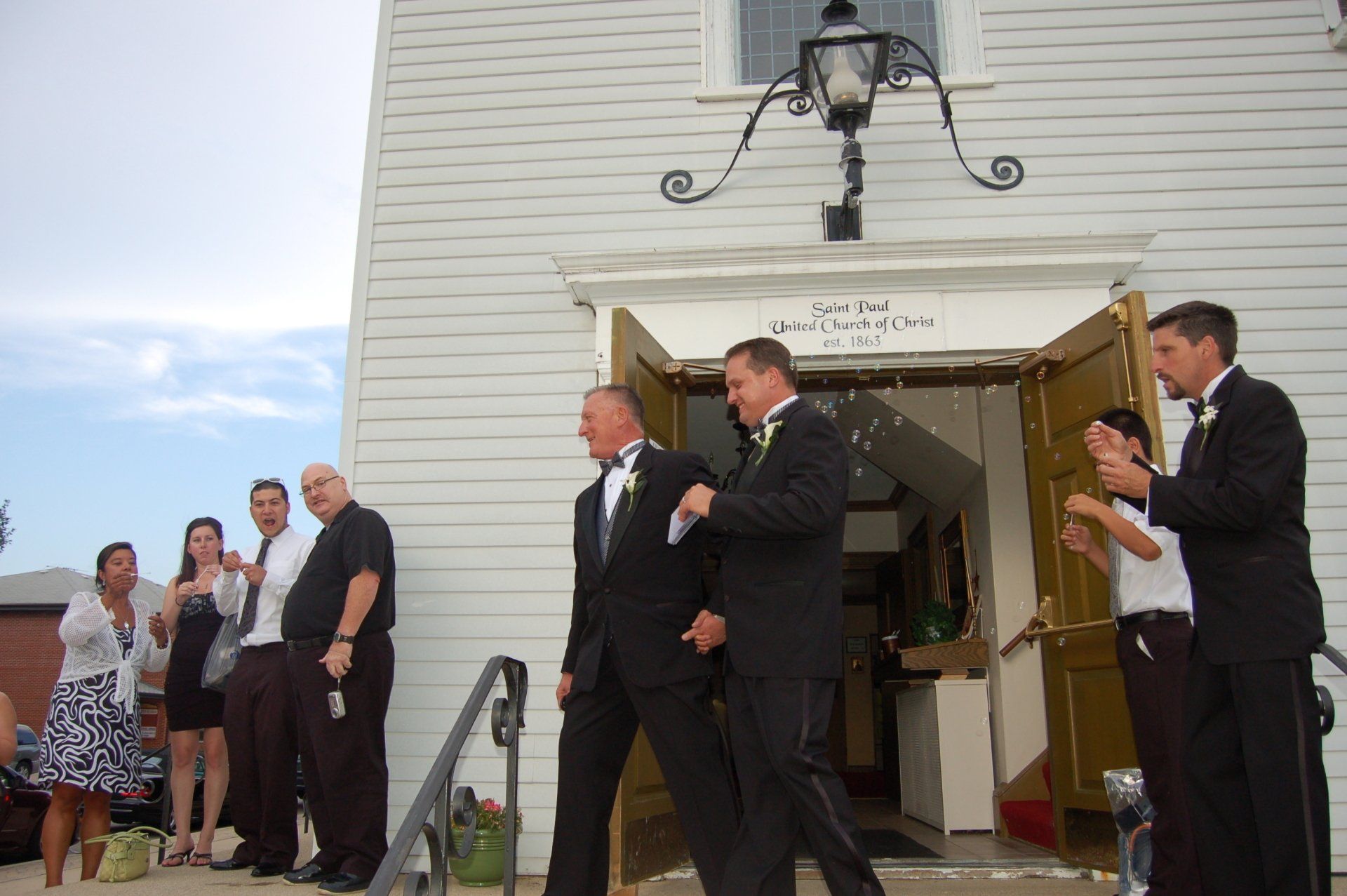 A group of men in suits are walking out of a church