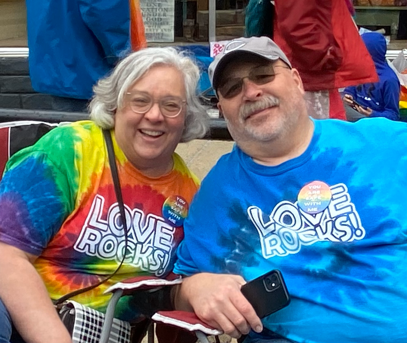 A man and a woman wearing tie dye shirts that say love rocks