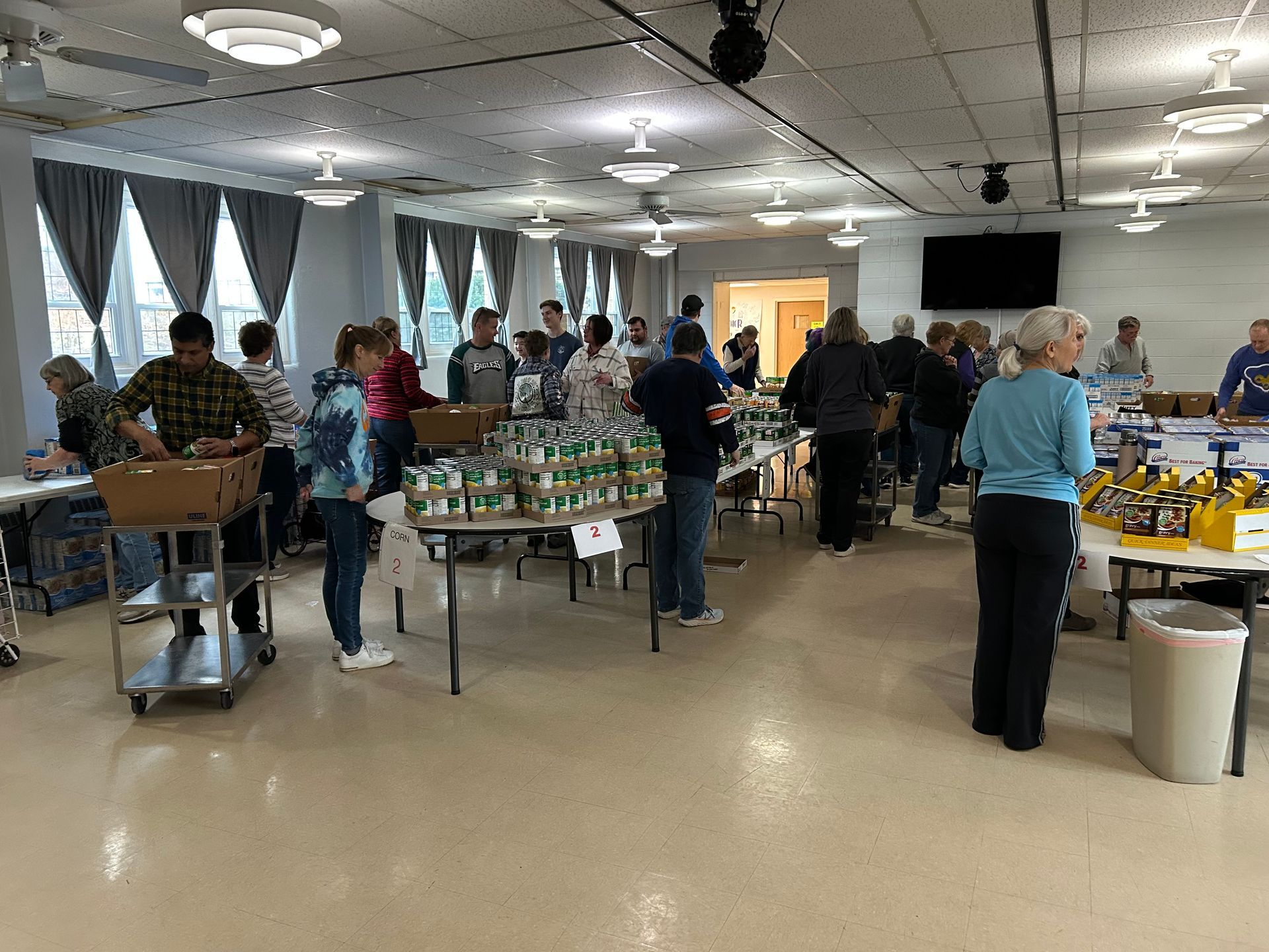 A group of people are standing around tables in a large room.