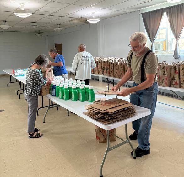 Volunteers sorting supplies on tables in a bright community hall