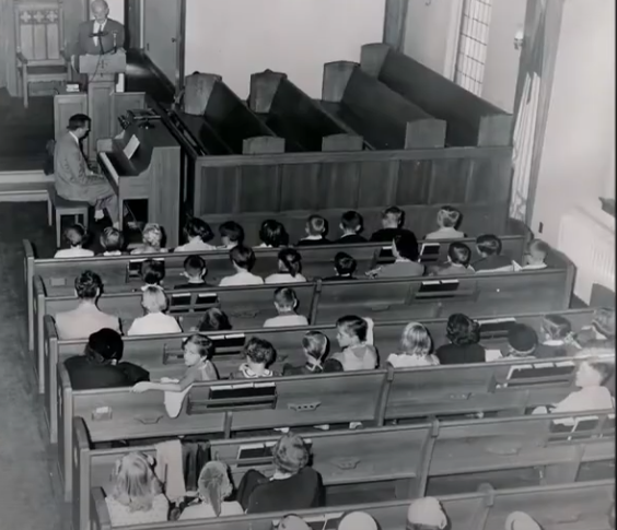A black and white photo of people in a church