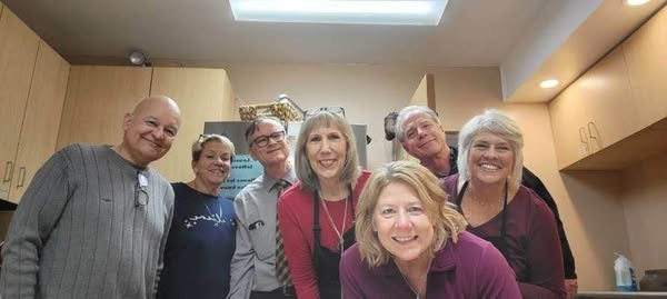 A group of people are posing for a picture in a kitchen.