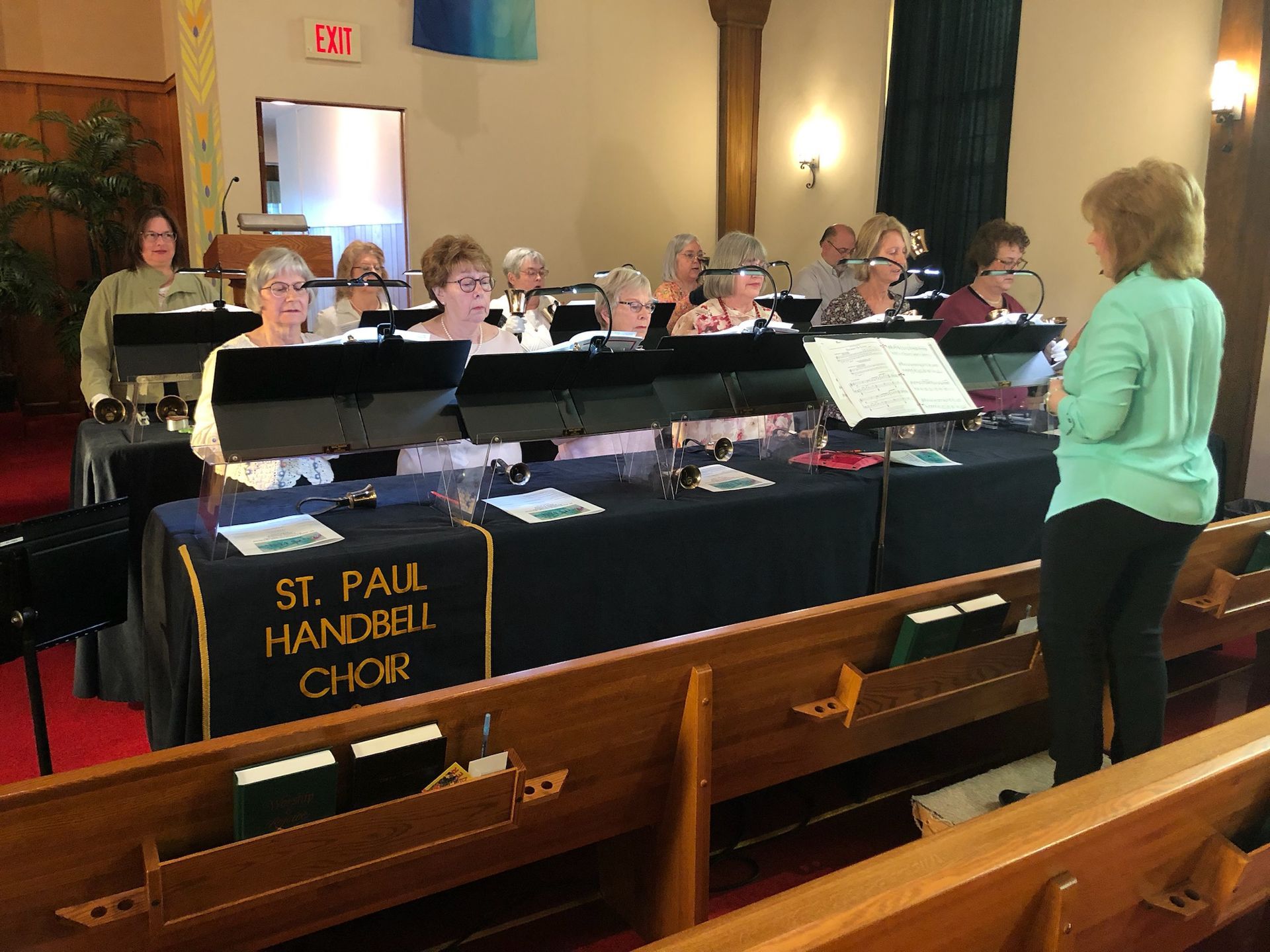 A woman stands in front of a st. paul handbell choir
