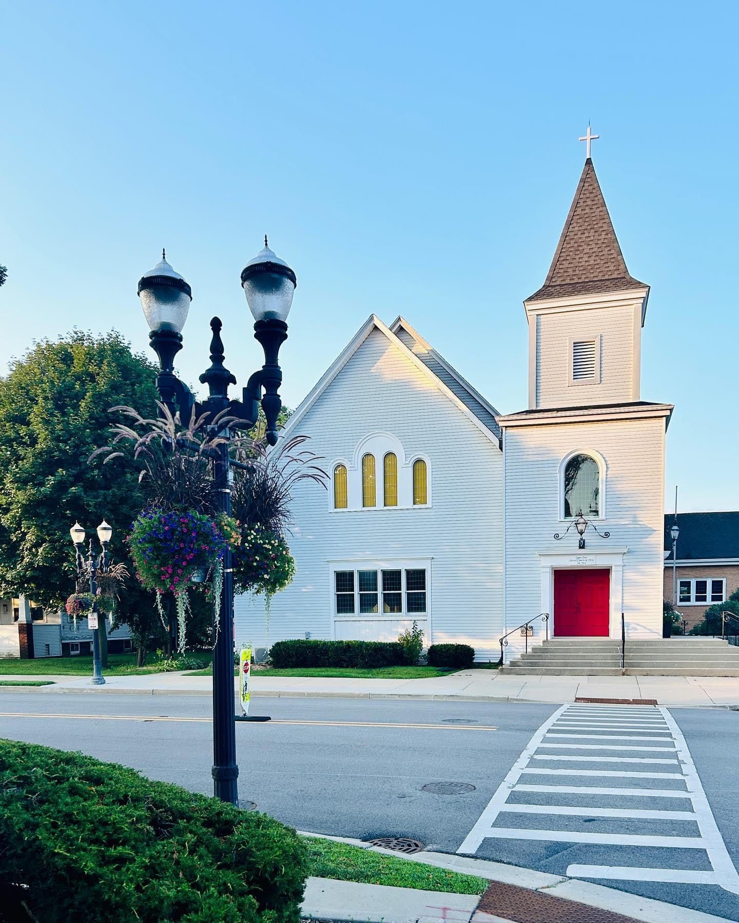 A white church with a red door and a clock tower