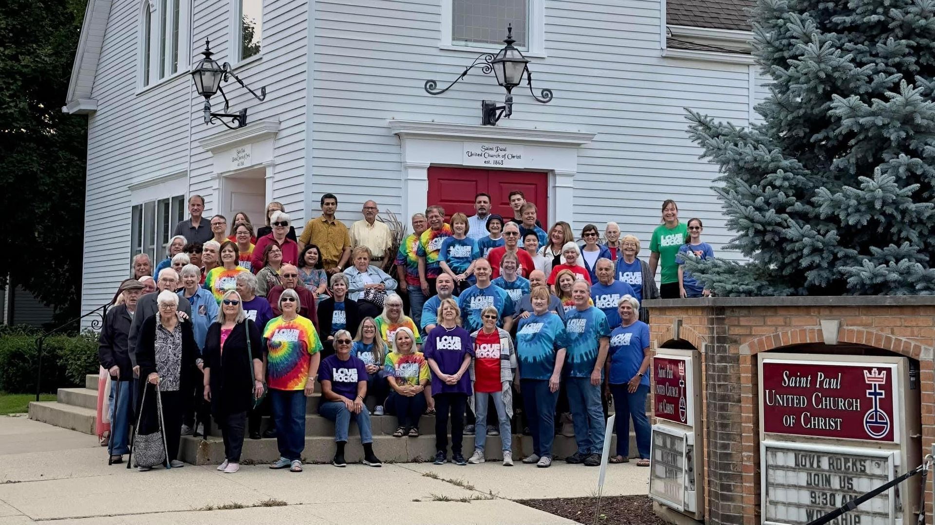 A large group of people are posing for a picture in front of a church
