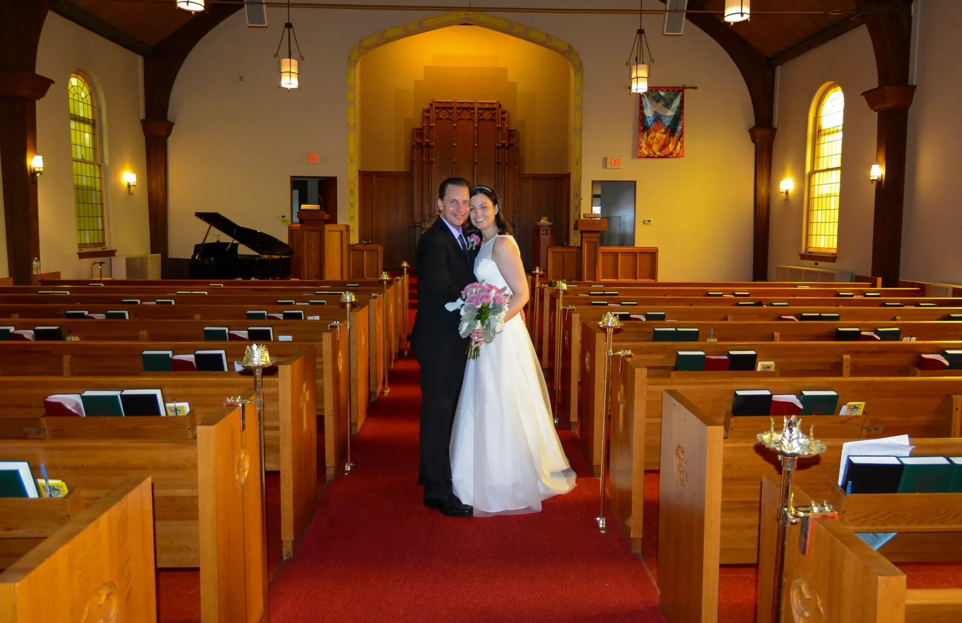 A bride and groom pose for a picture in a church