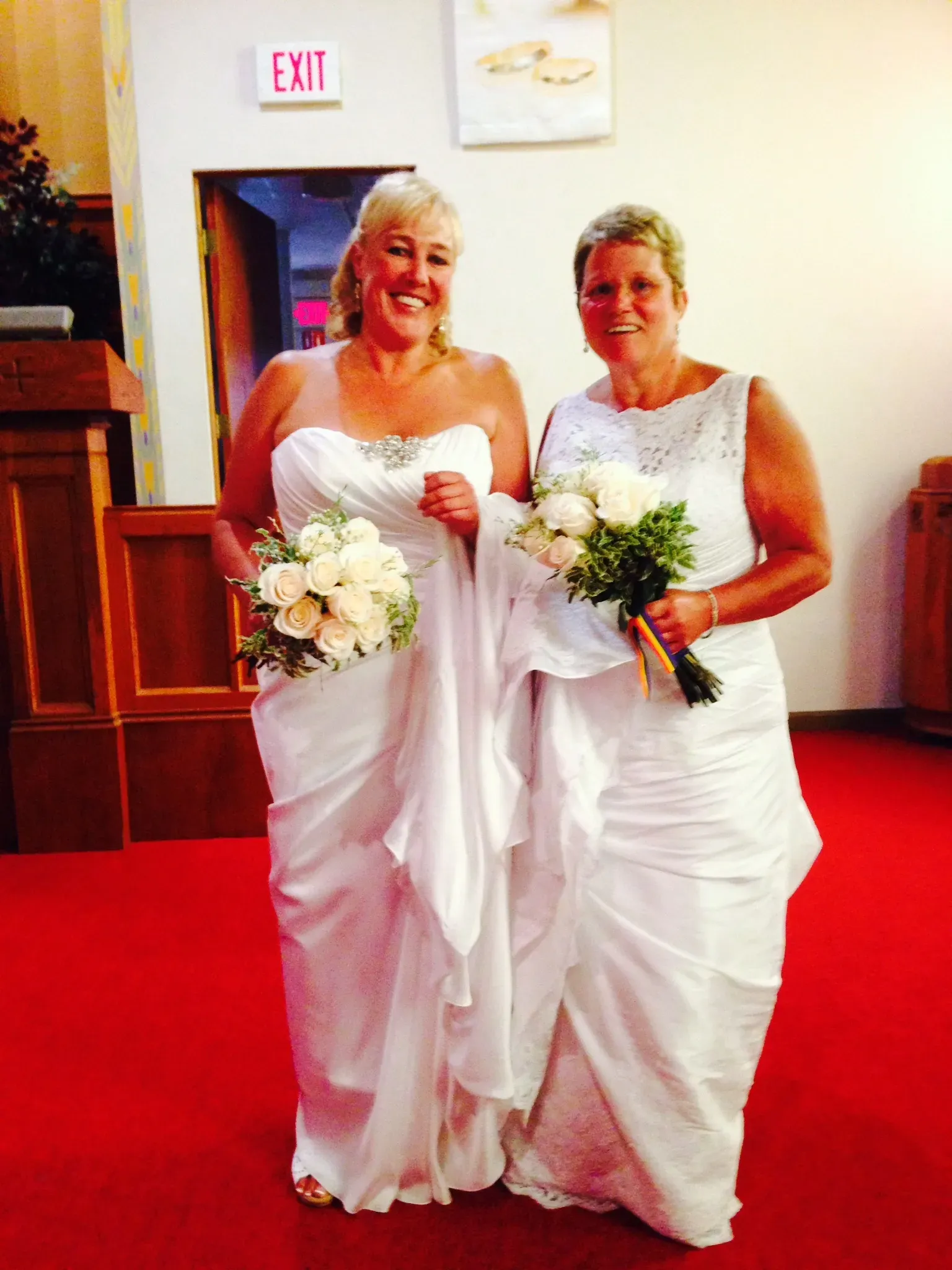 Two women are standing next to each other in front of an exit sign