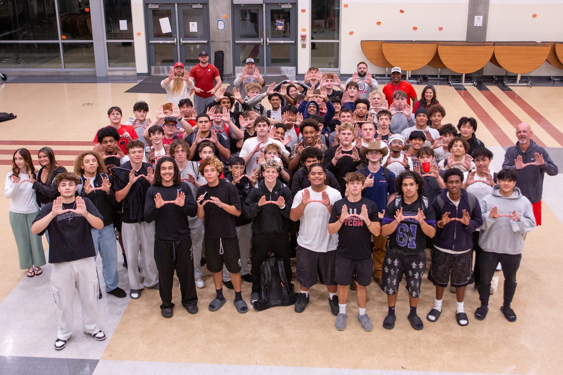 The Union High School football program gathered in the commons after the Full-Program Dinner, making the Union U hand sign.