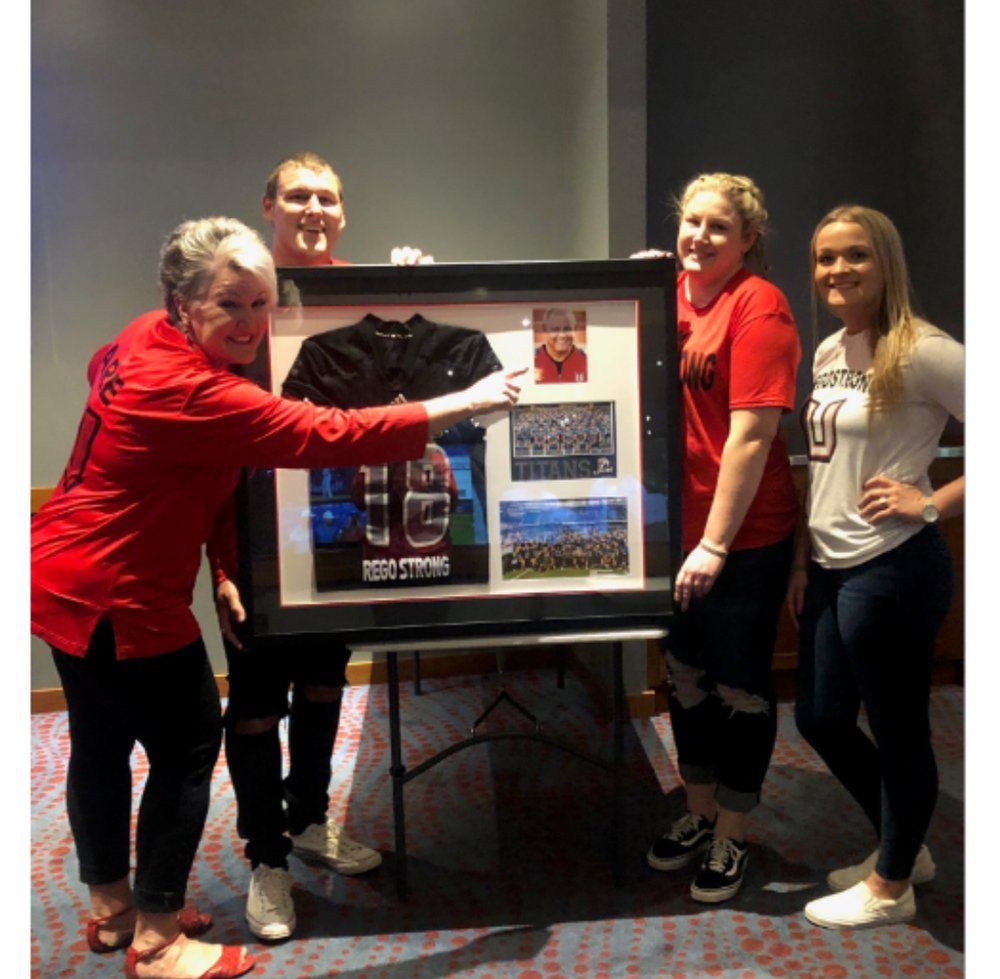 The Rego family presenting a framed REGOSTRONG memorial shadow box.