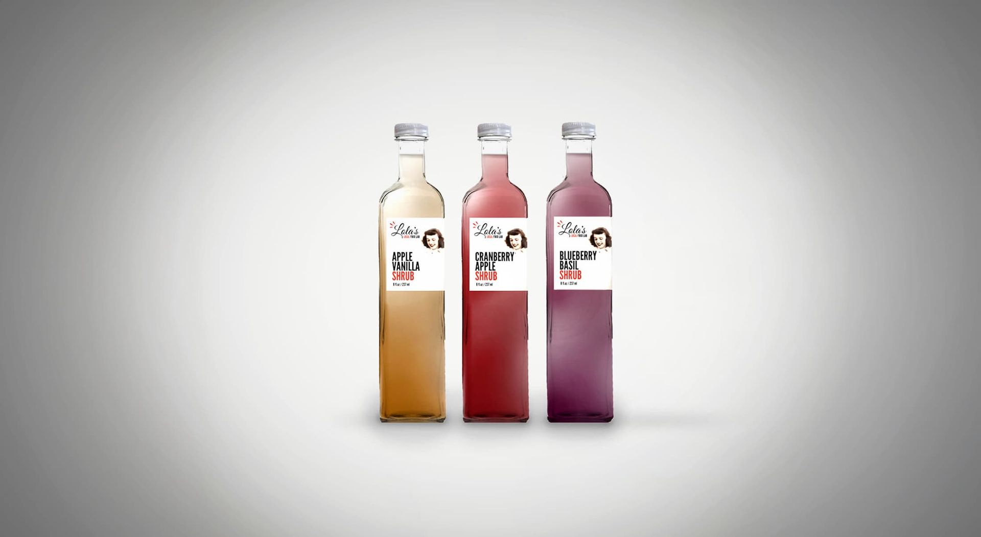 Three bottles of colorful liquid with labels, against a gray gradient background.