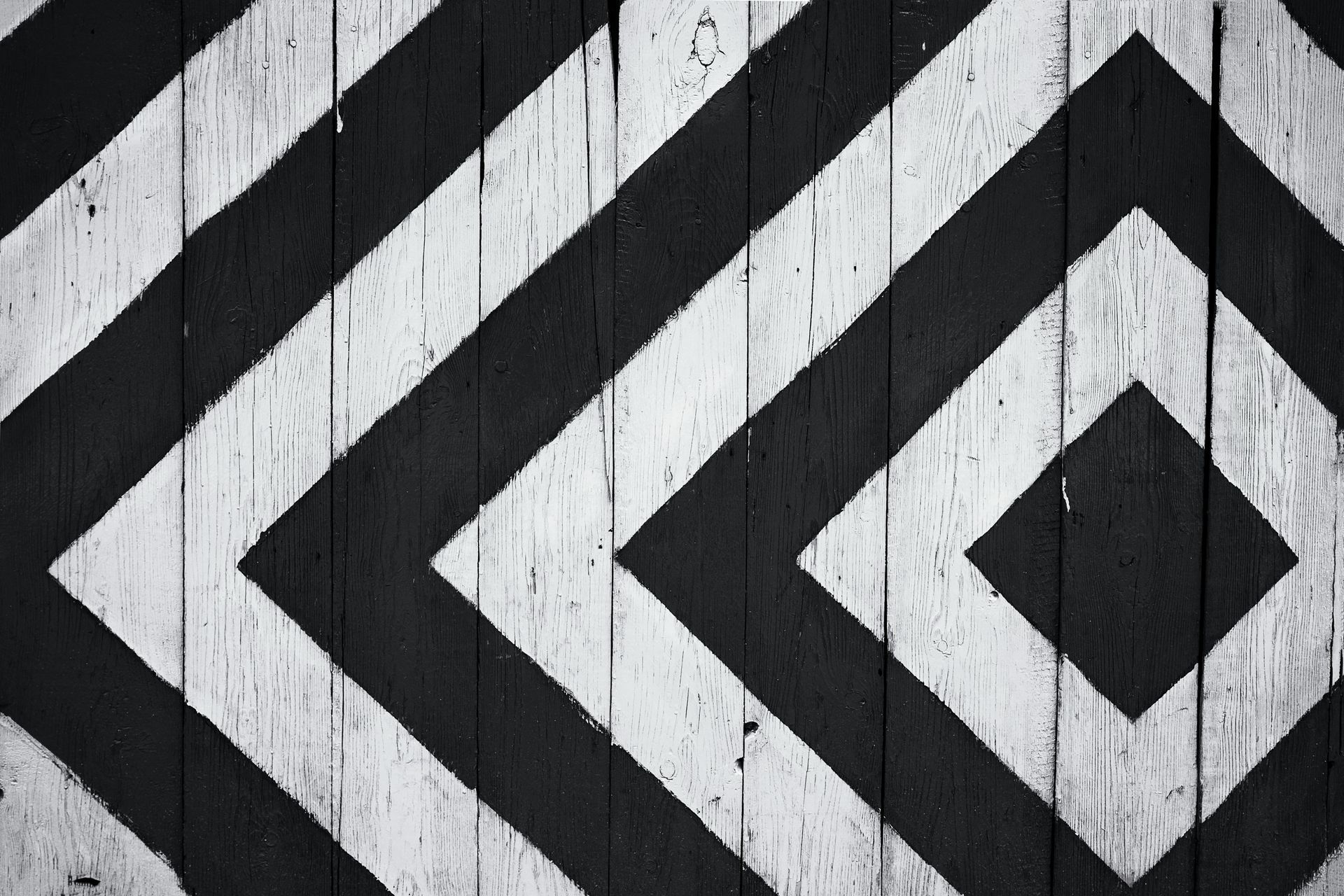 Black and white diamond pattern painted on weathered wooden planks.