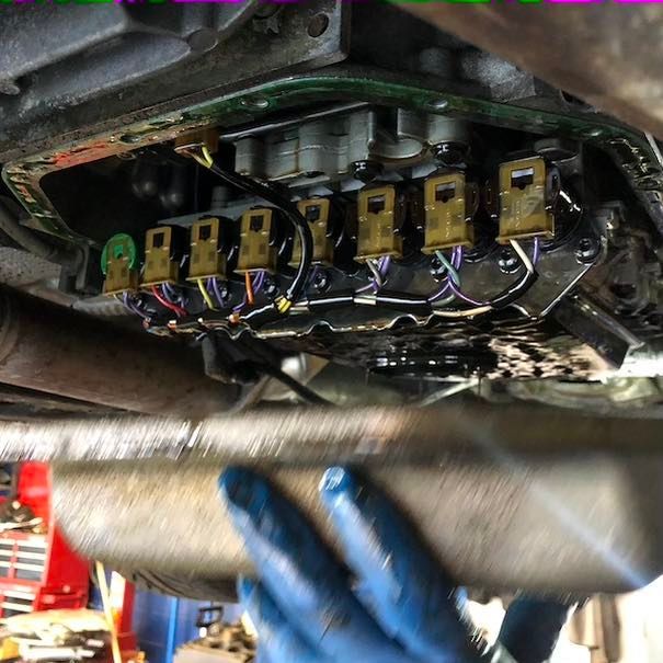 A person is working on the underside of a car.