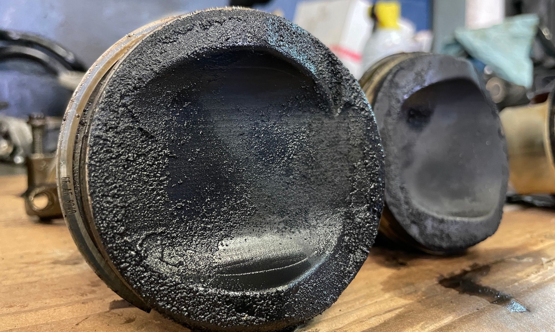 A close up of a dirty piston on a wooden table.