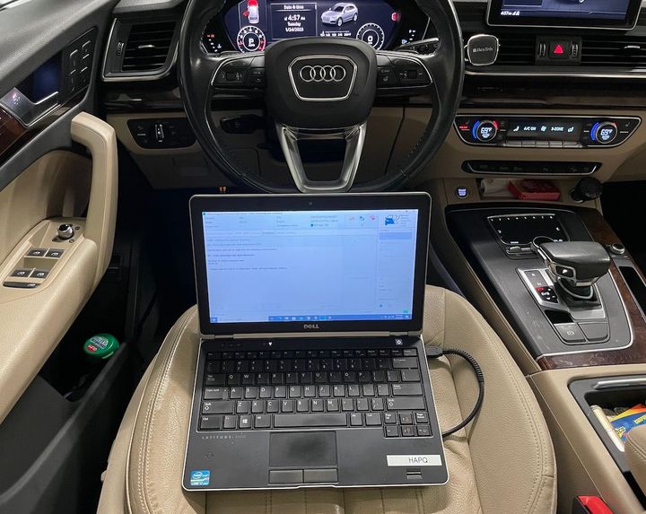 A laptop is sitting in the driver 's seat of an audi car