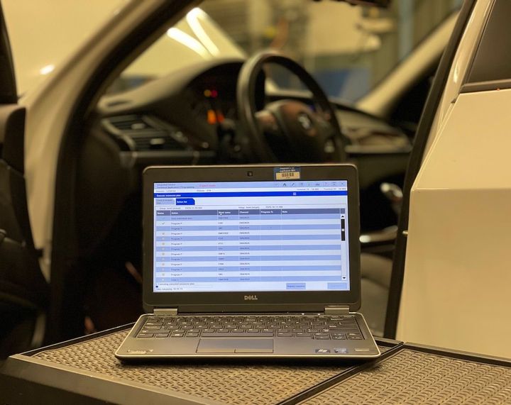 A dell laptop is sitting on a table in front of a car