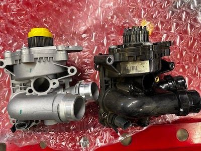 Two water pumps are sitting next to each other on a red surface.