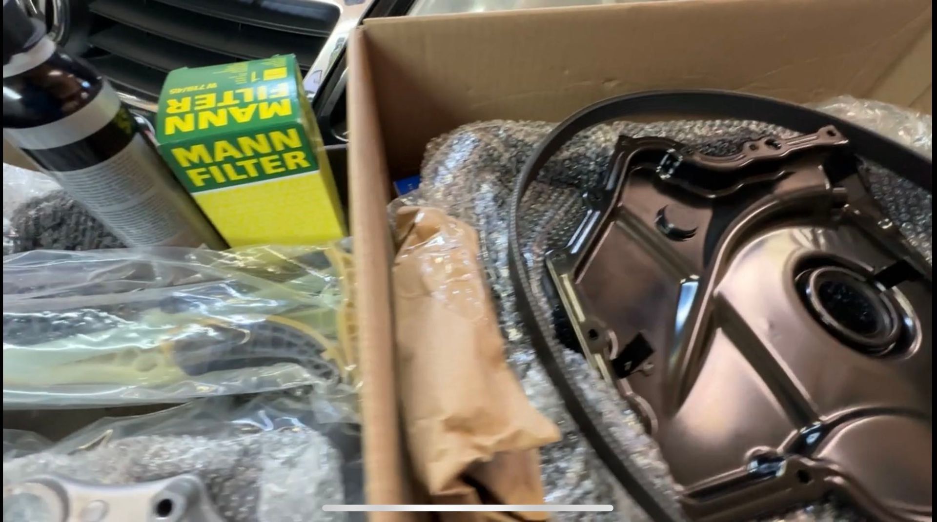 A box of mann filter is sitting on top of a pile of parts.