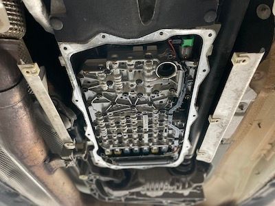 A close up of the underside of a car showing the transmission.