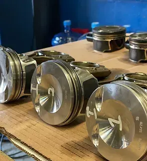 A row of pistons are sitting on top of a wooden table.