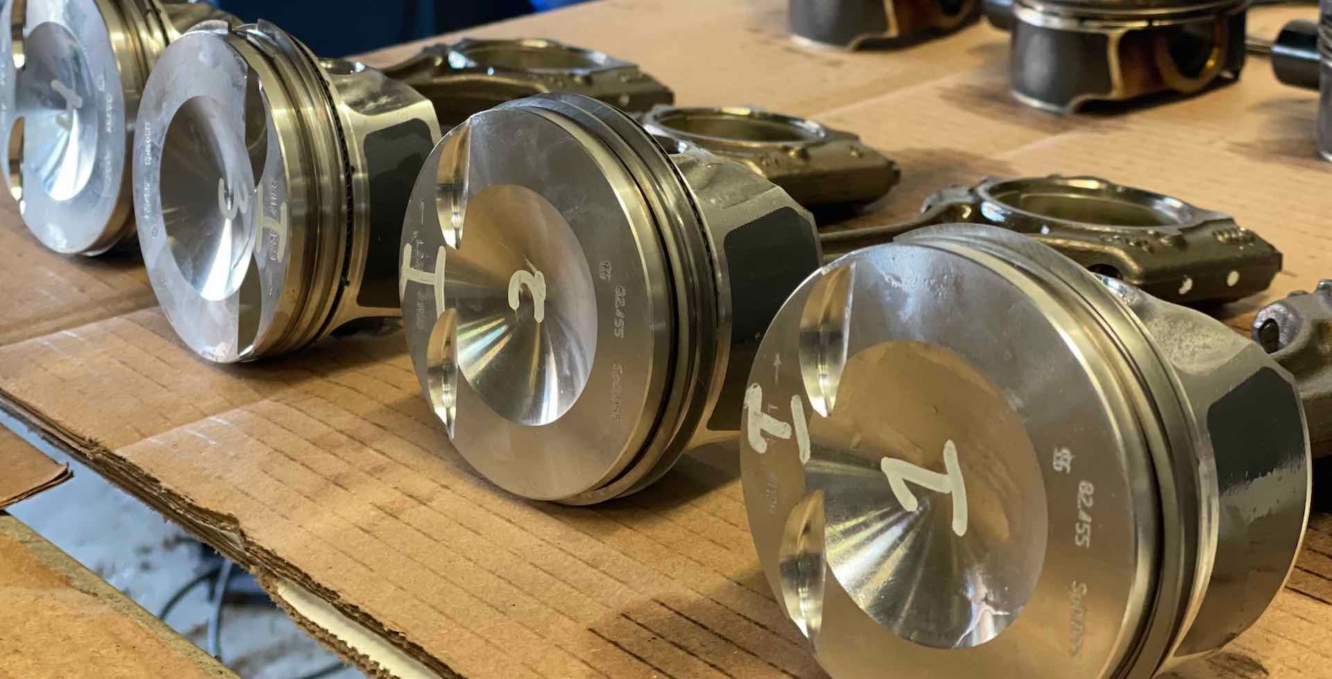 A row of pistons are sitting on top of a cardboard box.
