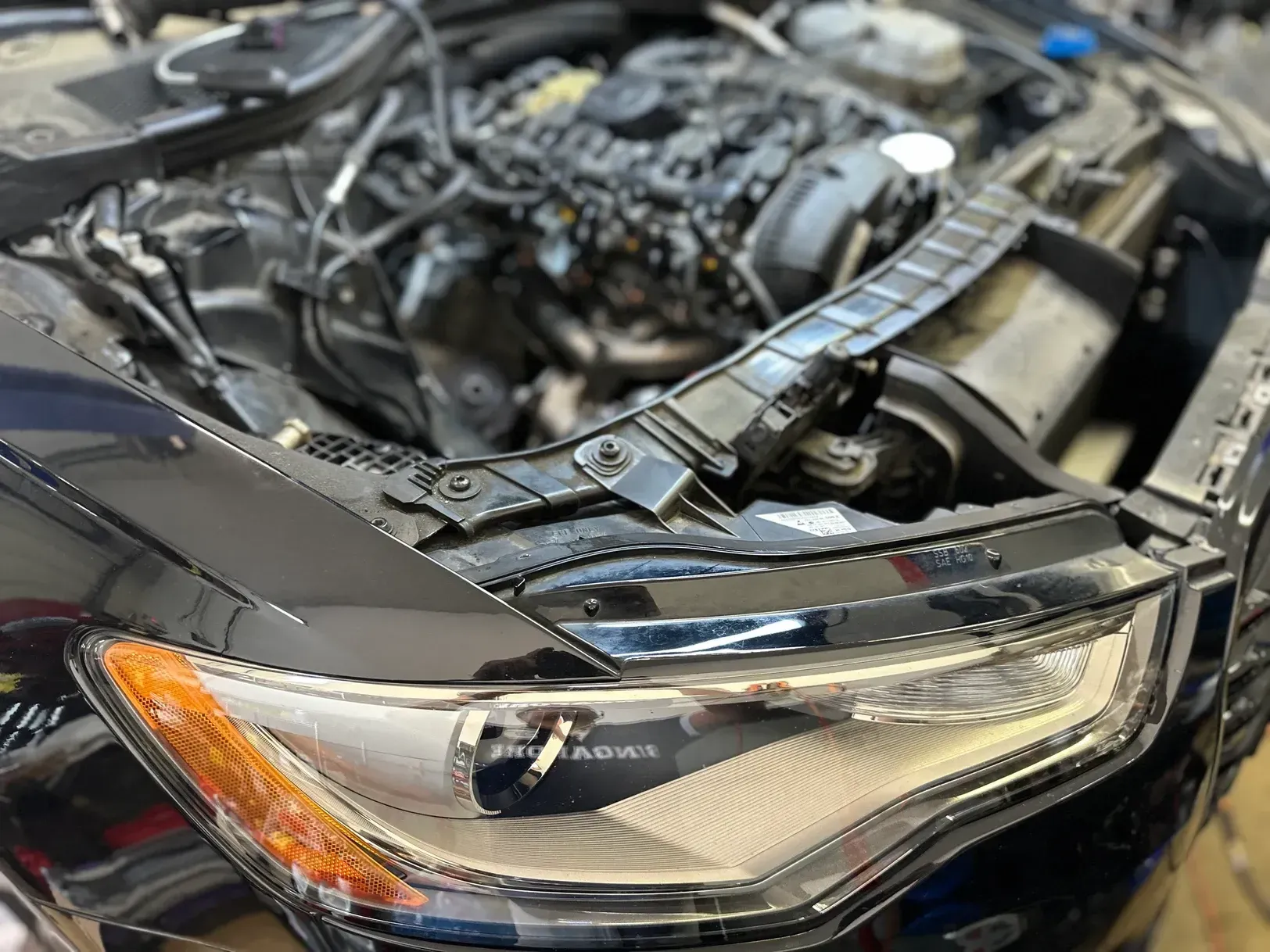 The hood of a black car is open and the engine is visible.