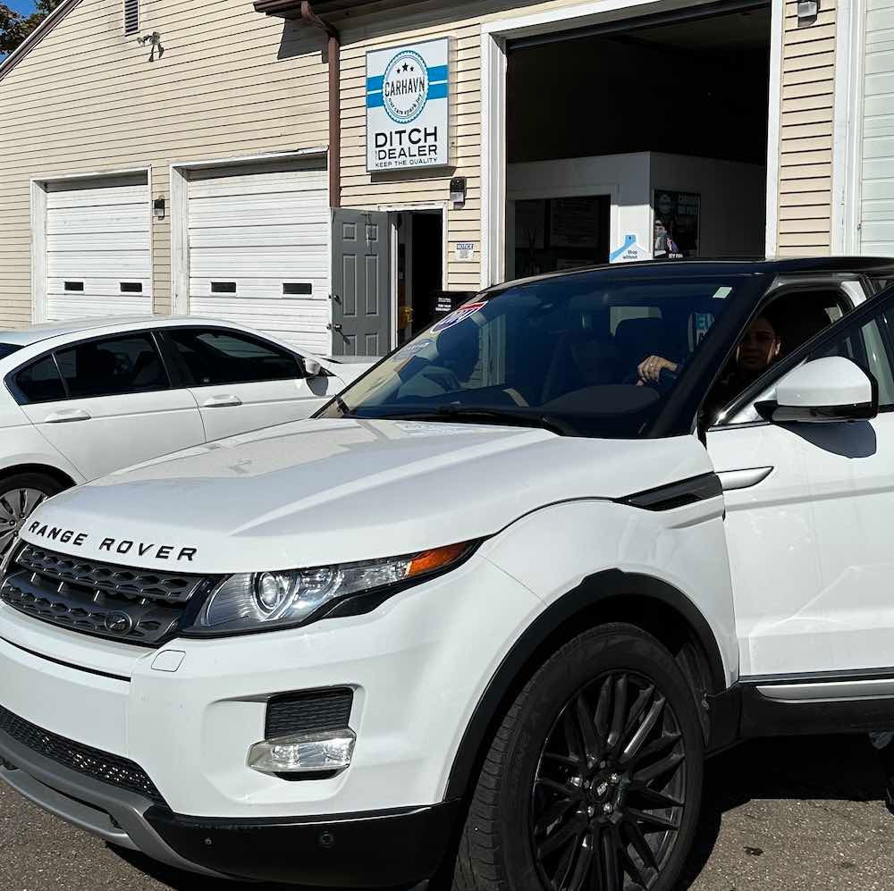 A white range rover is parked in front of a garage