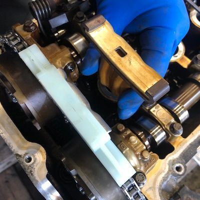A person wearing blue gloves is working on a car engine