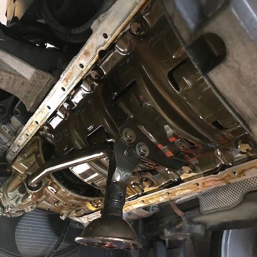 A close up of a car engine with oil coming out of it