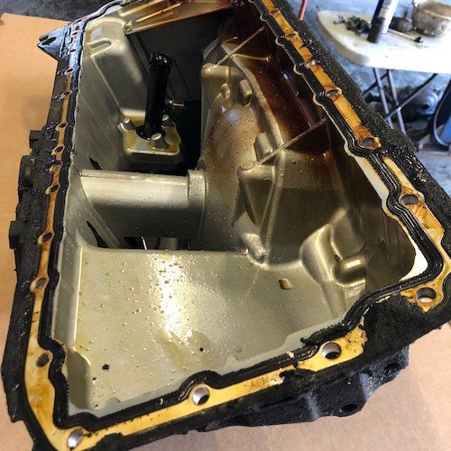 A dirty oil pan is sitting on a table.