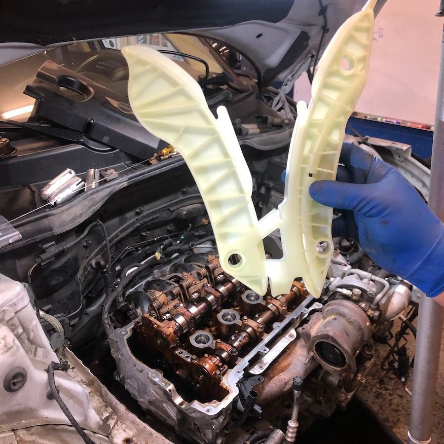 A person wearing blue gloves is working on a car engine