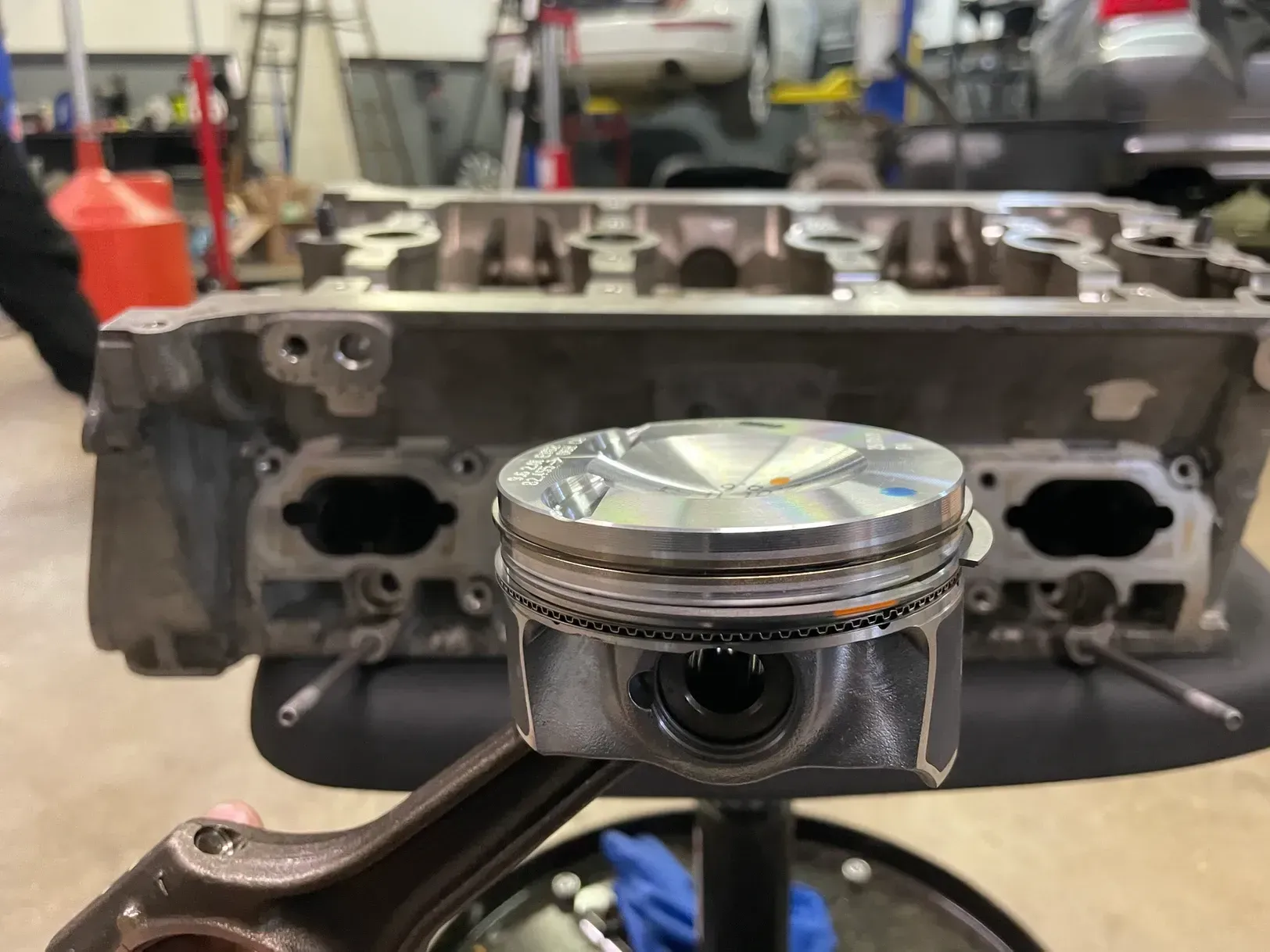 A piston is sitting on top of a crankshaft in front of a cylinder head.