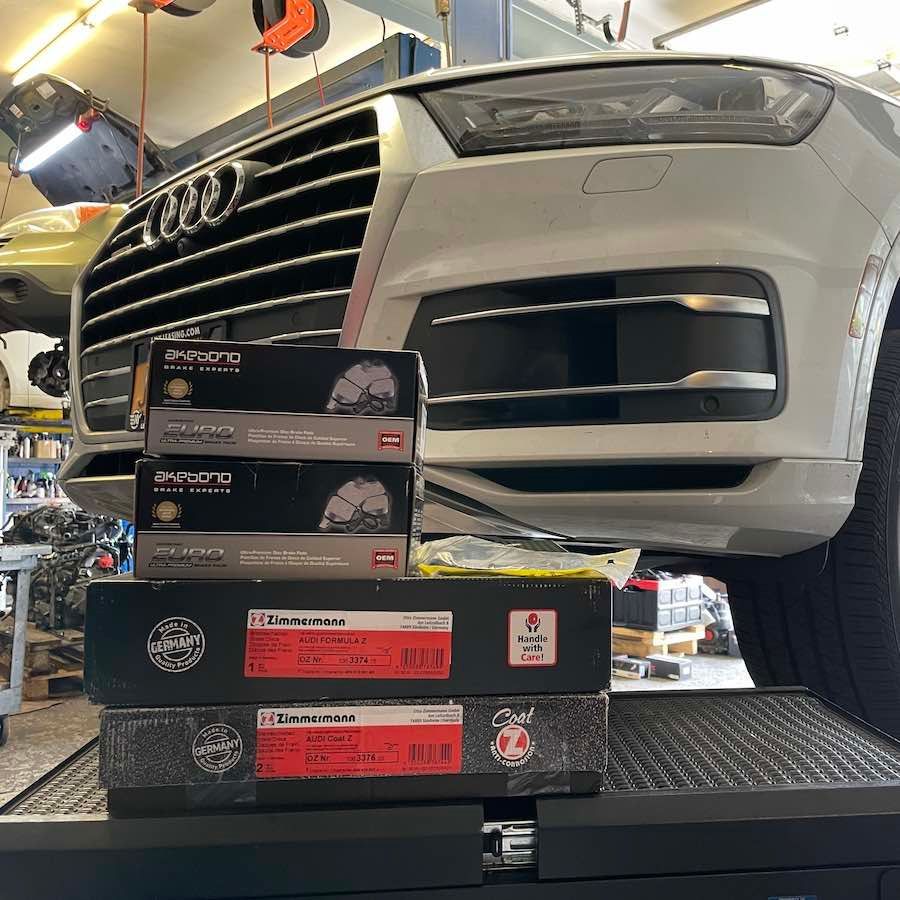 A white audi q7 is sitting on a lift in a garage.