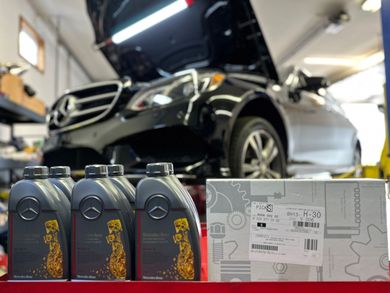 A mercedes is sitting on a lift in a garage next to bottles of oil