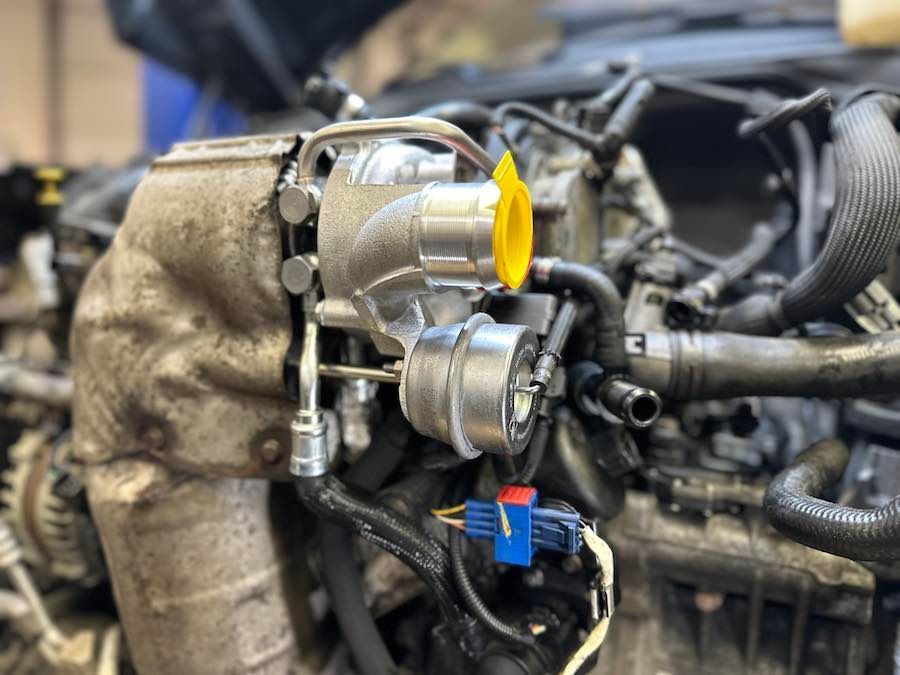 A close up of a car engine with a yellow cap on it.