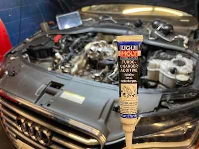 A tube of liqui moly turbo charger additive is sitting on top of a car engine.