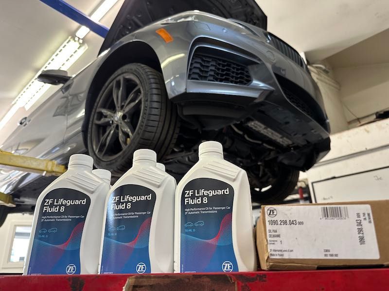 A car is sitting on a lift next to bottles of oil.