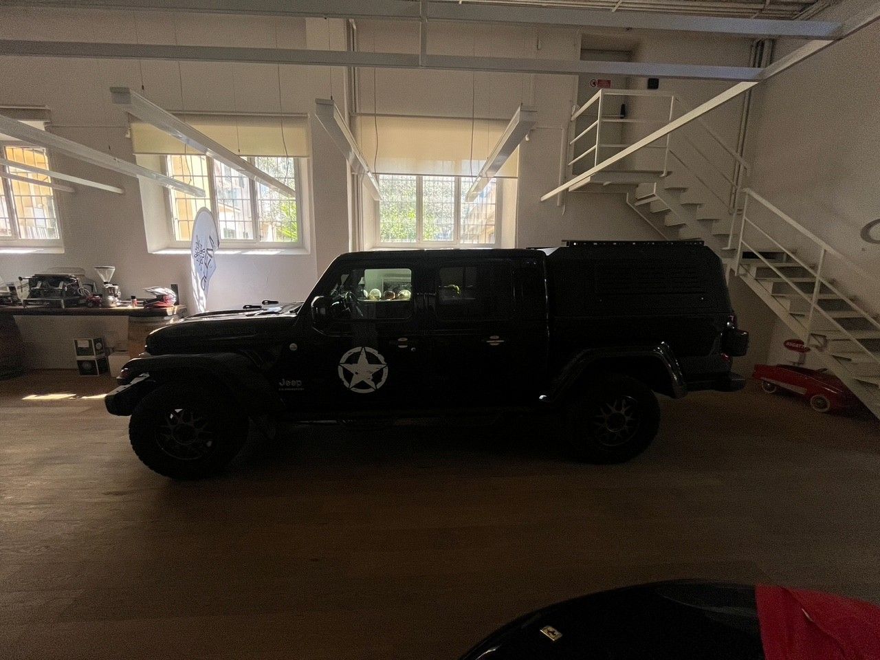 Jeep SUV nera parcheggiata all'interno di un garage luminoso, vicino a una scala bianca.