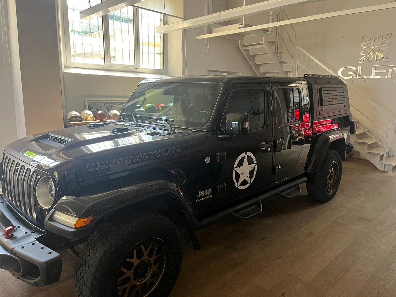 Jeep Wrangler nera all'interno di uno showroom luminoso, vista dal lato anteriore sinistro.