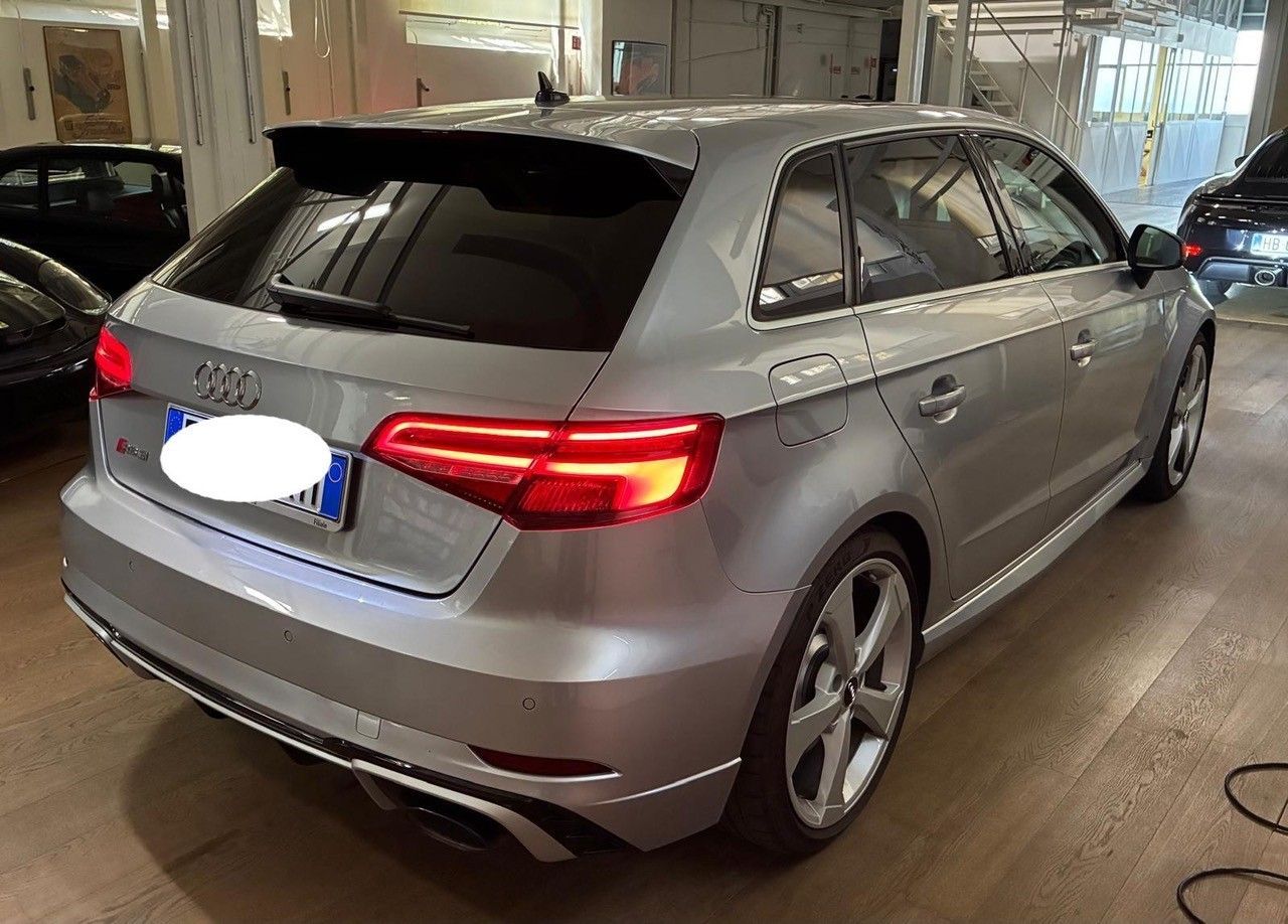 Audi hatchback argento parcheggiata all'interno di uno showroom o di un garage, vista posteriore